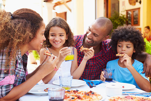 family eating meal at outdoor restaurant together, smiling